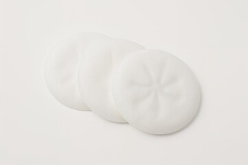Fototapeta premium Disposable cotton pads for facial cleansing and skin care on a plain white surface.