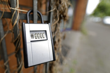 Close-up of a silver combination padlock attached to a metal fence, outdoors.