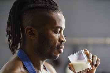 A man with dreadlocks savors a glass of milk, embodying relaxation and comfort. This simple beverage adds to his tranquil moment in a cozy setting, inviting calmness and mindfulness.