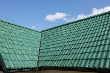 Fototapeta premium Hipped roof of a countryside home covered with green soft bitumen shingles