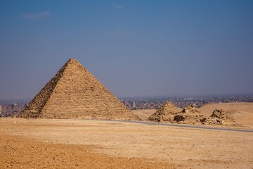 View of the Giza pyramids under a clear blue sky with the cityscape in the background