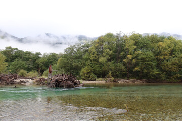 Kamikochi, Japan – 5 Oct 2024: scenic view of Northern Japan Alps, featuring Azusa River, lush forests, towering peaks, Kappa Bridge, Myojin Pond, alpine wilderness, Chubu Sangaku National Park.