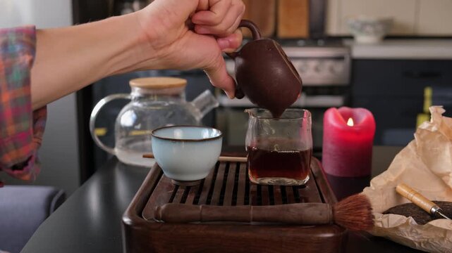 Traditional Chinese tea ceremony at home, pouring puer tea with gongfu cha method in authentic kitchen lifestyle.