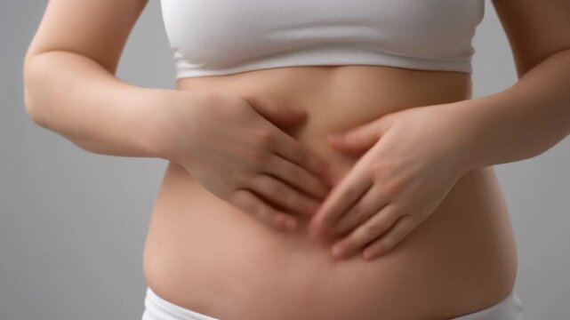 A woman gently rubbing her stomach and side, checking for cellulite and excess subcutaneous fat 