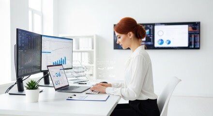 A businesswoman working at a desk with multiple monitors and a laptop.