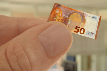 Concept de restriction budgétaire avec une main tenant un billet de cinquante euros miniature en...
