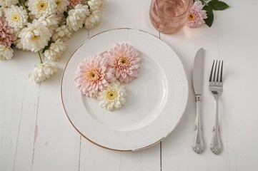 Chrysanthemum blooms next to cutlery on a rustic white wooden surface
