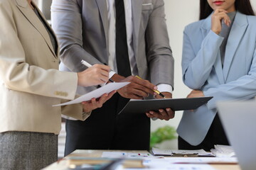 Business team is analyzing financial documents, pointing at charts and graphs, discussing strategies and collaborating on a project during a corporate meeting.