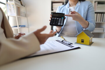 Real estate agent holding a calculator is bidding on a house for a female client. Businesswoman,...