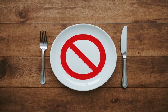 No dining allowed sign on a wooden surface with cutlery, top-down perspective