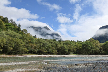 Kamikochi, Japan – 5 Oct 2024: Rocky bank of the emerald Azusa River in Kamikochi, Northern Japan Alps, surrounded by mountains and forests. Popular for hiking, sightseeing, and nature photography.