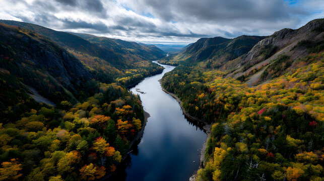 A panoramic view of a river winding through autumn muntain valleys, with colorul foliage lining the bank.