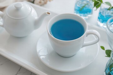 Fototapeta premium A White Cup Filled with Blue Tea on a Matching Saucer and Tray, Evoking a Calm Atmosphere. Beneficial Beverage with Therapeutic Qualities. Herbal Remedy. Tea Gathering.