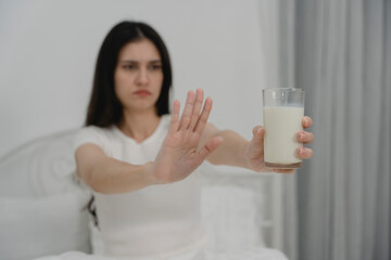 Woman refusing a glass of milk with hand gesture, showing dairy allergy or lactose intolerance....