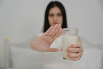 Woman refusing a glass of milk with hand gesture, showing dairy allergy or lactose intolerance....