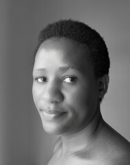 Obraz premium B&W studio portrait of a confident woman looking at the camera with a calm expression. Suitable for concepts of confidence, strength, authenticity, and professional identity.