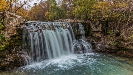 Fototapeta premium Water rushing over rugged rocks near a quiet spring-fed lake