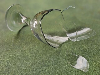 Broken glass cup, sharp shards, isolated on green background.