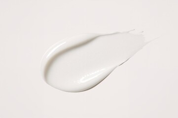 Texture of white facial cosmetic cream. Isolated lotion smear on plain background. Skincare beauty product application.
