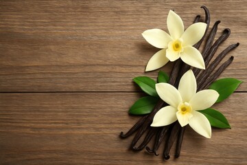 Fototapeta premium Sweet vanilla beans, colorful flowers, and verdant leaves displayed on a wooden table, perfect for adding personalized text