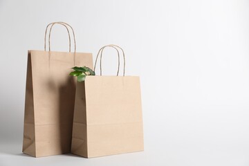 Eco friendly packaging. Paper bags and leaves on white background, space for text