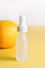 Vitamin C concept: lemon and frosted cosmetic bottle on yellow background.