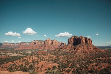 Naklejka premium Helicopter Flying Over Rocky Hills Under Clear Blue Sky