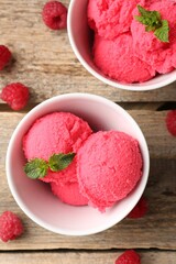 Delicious raspberry sorbet with mint in bowls and fresh berries on wooden table, flat lay