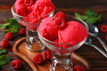 Delicious raspberry sorbet in dessert bowls, mint and fresh berries on wooden table, closeup