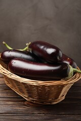 Many ripe eggplants in basket on wooden table