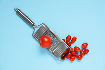 Fresh tomatoes and grater on light blue background, flat lay