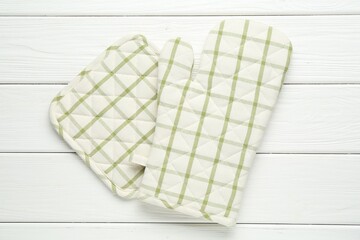 Oven glove and potholder on white wooden table, top view