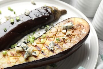Slices of grilled eggplant with green onion and blue cheese on table