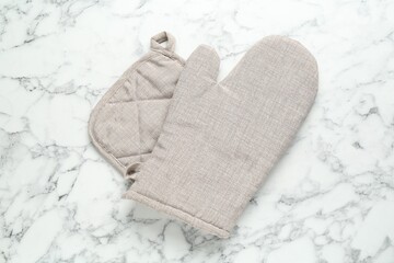 Oven glove and potholder on white marble table, flat lay