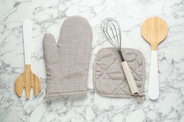 Oven glove, potholder and other kitchen utensils on white marble table, flat lay