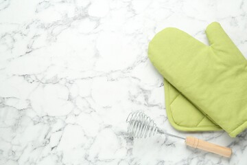 Oven glove, potholder and whisk on white marble table, flat lay. Space for text