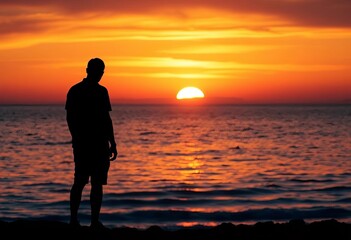Fototapeta premium Solitary figure silhouetted against a vibrant sunset over the ocean, ocean, reflection