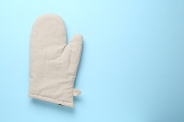 One oven glove on light blue background, top view. Space for text