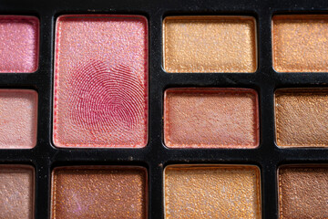 Fototapeta premium Close-up Macro Shot of Shimmery Eyeshadow Palette with Fingerprint Detail; Warm, Glamorous Tones.