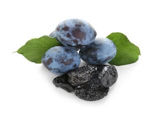 Dried prunes, fresh plums and green leaves isolated on white