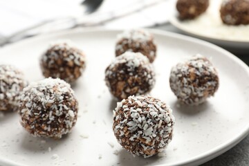 Tasty chocolate candies with nuts and coconut flakes on grey table, closeup
