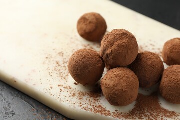 Tasty chocolate candies with cocoa powder on black table, closeup. Space for text