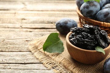 Dried prunes and fresh plums on wooden table, closeup. Space for text