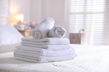 Stack of clean towels on bed linens at home, closeup