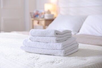 Stack of clean towels on bed linens at home, closeup