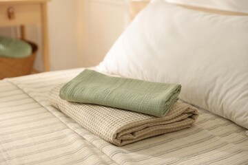Stack of clean towels on bed linens at home