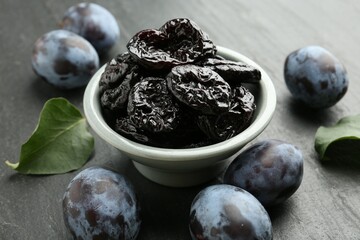 Dried prunes and fresh plums on black table, closeup