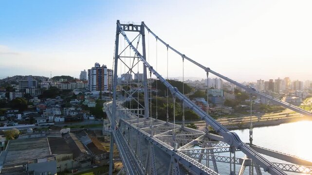 Magnificent aerial view of the Herc&iacute;lio Luz suspension bridge in Florian&oacute;polis, Santa Catarina, with sunlight penetrating its iron structure and cable-stayed cables, performing challenging stunts