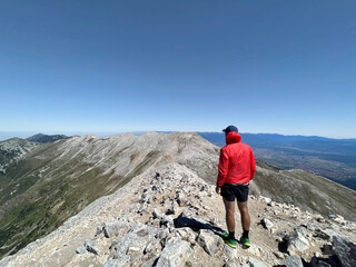 Fototapeta premium Hiker man standing on a rocky mountain peak looking the view . Pirin Mountain ,Bulgaria 