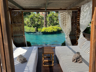 Loungers with white curtains and pool view 